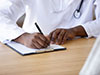 photo of a nurse in lab coat writing with a pencil