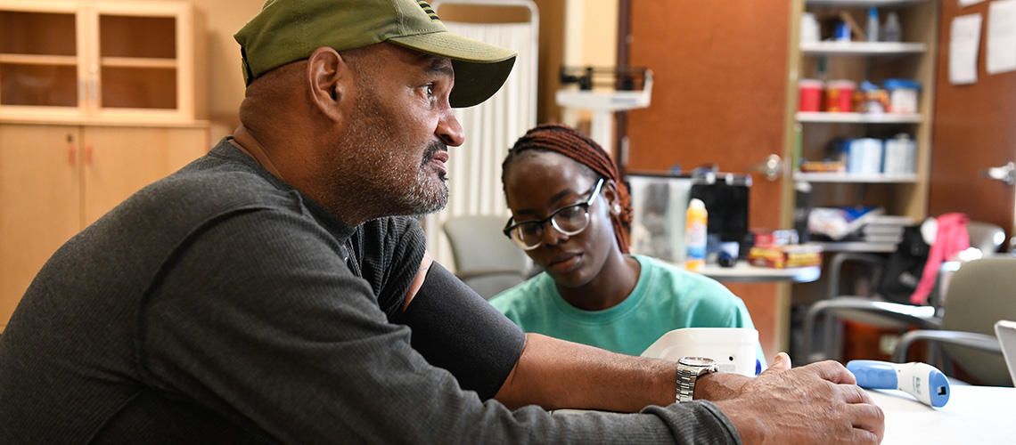 A man has his blood pressure taken by a student