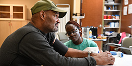 A female student takes the blood pressure of a male patient