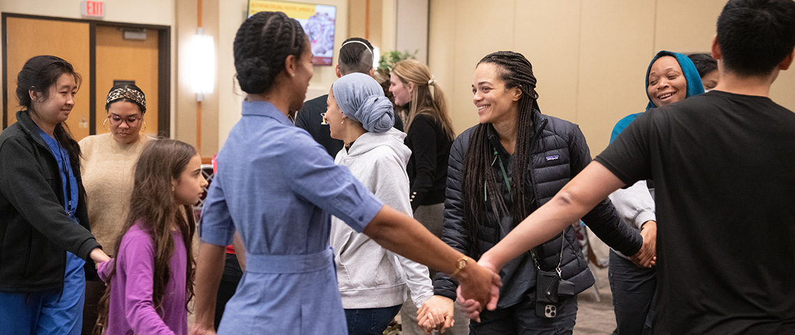 Faculty, staff, and students dance in a circle holding hands