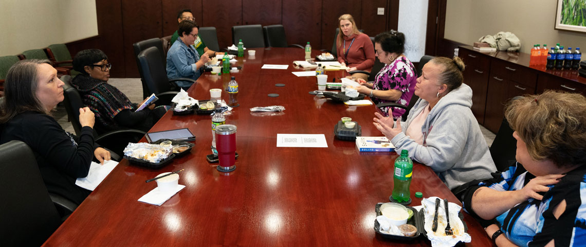 employees sit around a conference table discussing a book