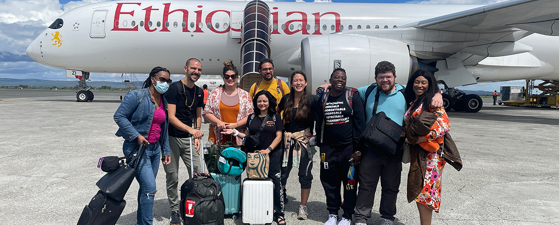 Students pose in front of a plane that says 