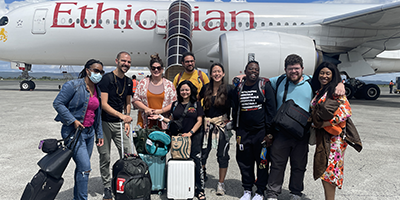 Students pose in front of a plane that says 