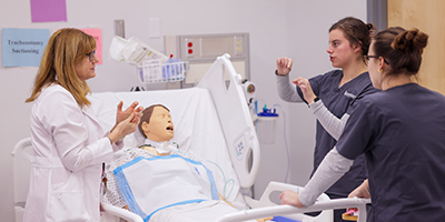 Tow students talk with a female professor about a sim patient