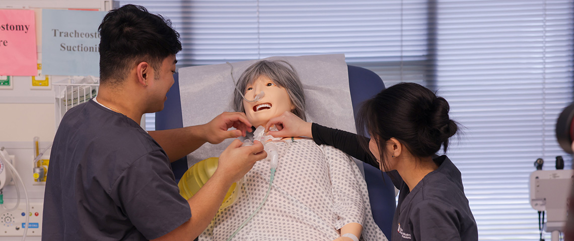 a male and a female student use a breathing valve mask on a sim patient