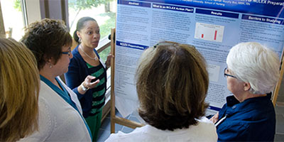 nurses standing around a poster and discussing it