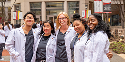 Students pose outside the UMSON building in white coats