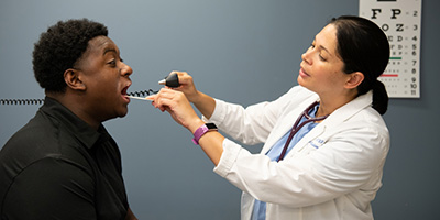 An NP checks the throat of a male patient