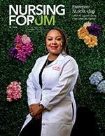 Woman in white coat sits in front of floral wall