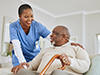 A female nurse chats with an elderly male patient with a cane