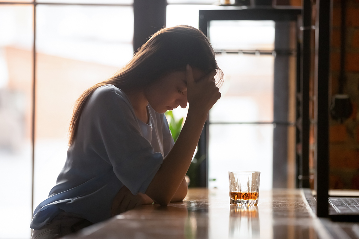 A woman at a bar with a drink next to her.