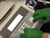 a gloved hand uses equipment in the lab
